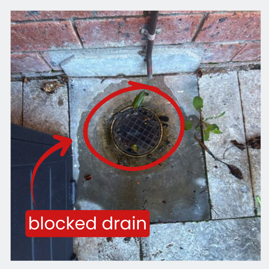 External grated drain beside a brick wall and paved area at a single-level townhouse in Stirling.