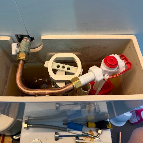 Open toilet cistern with internal parts and plumbing tools visible at an Edinburgh Avenue apartment.