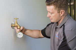 JML Trades plumber inspecting exposed pipework in a home.